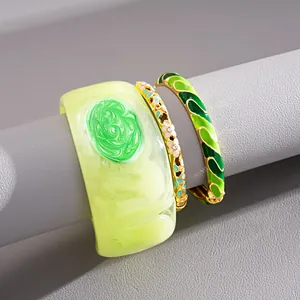Close-up of colorful dopamine style enamel and resin bracelet set on grey display stand.