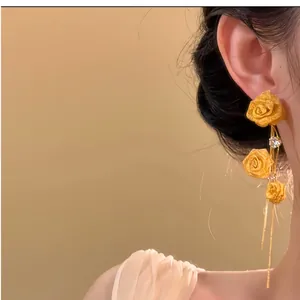Detailed view of elegant golden rose tassel earrings with zircons on model