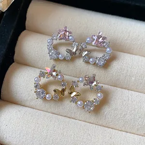 Nahaufnahme von 18 Karat vergoldeten Sternohrringen mit Zirkonia, Perlen und Schmetterling