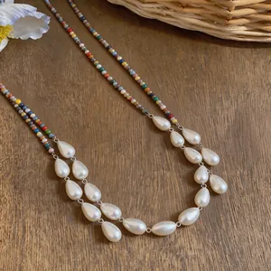 Detail view of vintage teardrop pearl necklace with colorful ethnic beads on wood surface