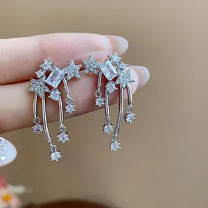 Macro dettaglio di eleganti orecchini a stella d'argento con gocce di zirconi scintillanti.