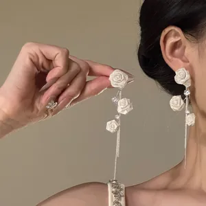 Détail de boucles d'oreilles roses en tissu blanc élégantes avec de longs glands en argent