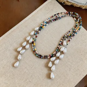 Detail view of ethnic beaded necklace with elegant white teardrop-shaped faux pearls