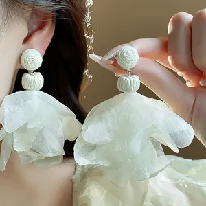 Close-up of elegant white chiffon flower tassel earrings for a bohemian fashion look