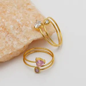 Detailed macro view of heart and round pink CZ gold rings on peach mineral stone