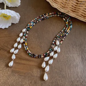 Detail shot of multi-strand colorful beaded necklace with elegant white pearl drops.