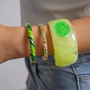 Detailed view of three green dopamine-style enamel and resin bangles worn on a wrist