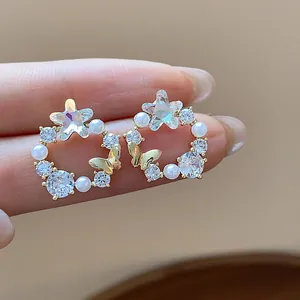 Detailansicht der 18k vergoldeten Stern- und Perlenohrringe mit Schmetterling.