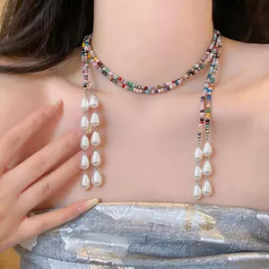 Detailed close-up of a colorful beaded necklace featuring elegant white teardrop pearls.