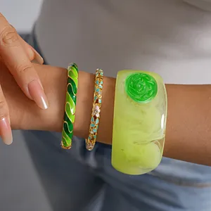 Macro detail of three stacked green enamel and resin bangles in various textures