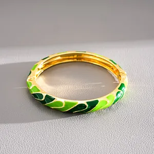 Close-up macro view of a gold-plated bangle with detailed green wave enamel finish