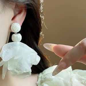 Elegant close-up detail of white chiffon flower earrings with bohemian aesthetic design