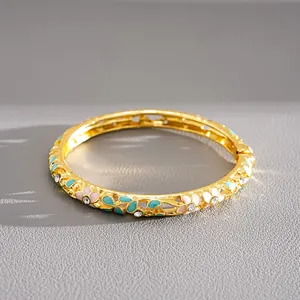 Close-up of gold-plated bangle with colorful enamel floral patterns and crystals