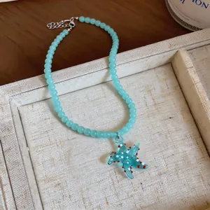 Detailed macro shot of a blue beaded vacation necklace with a glass starfish pendant