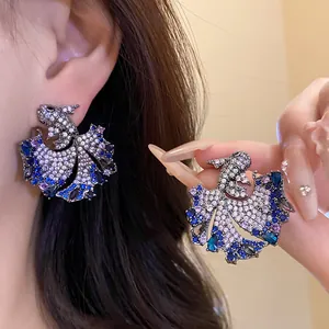 Detailed close-up of exquisite fish-shaped earrings encrusted with blue and clear zircons.