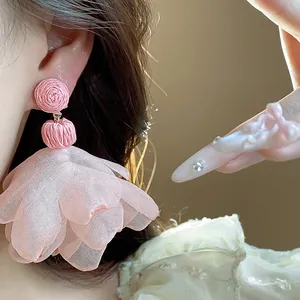 Detailed view of bohemian style pink chiffon flower tassel earrings on model
