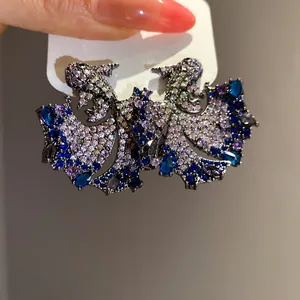 Macro view of vintage koi fish stud earrings encrusted with blue and purple zircon stones.