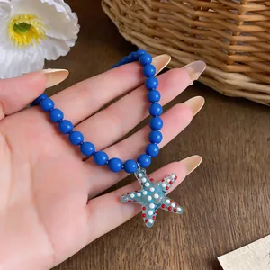 Detailed view of a blue beaded necklace featuring a spotted glass starfish pendant.