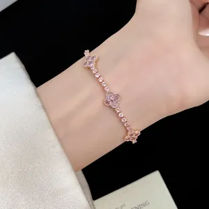 Close-up detail of a delicate rose gold bracelet featuring pink zircon four-leaf clovers