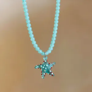 Close-up of a blue beaded necklace with a glass starfish pendant and red white dots.