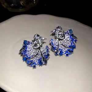 Detailed close-up of zircon-encrusted carp stud earrings with blue and purple stones.