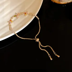 Detail of a gold adjustable bracelet with colorful zircon lucky clover flowers.