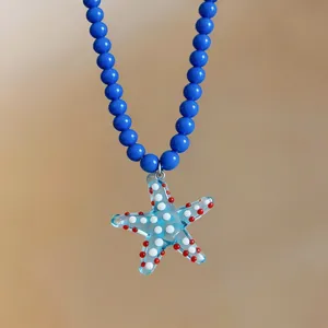 Detailed close-up of a blue beaded necklace with a spotted starfish pendant for beach vacations.