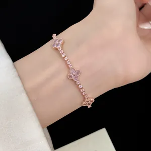 Close-up of elegant rose gold clover bracelet with pink zircons on wrist