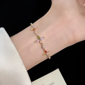 Detailed macro view of gold clover bracelet with colorful cubic zirconia stones on wrist