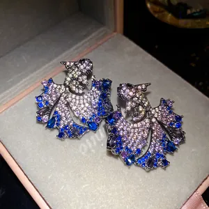 Detailed close-up of luxury zircon koi fish stud earrings with blue and purple stones