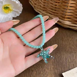 Detail view of a light blue beaded necklace with a charming starfish pendant for beach wear