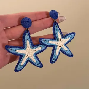 Detailed view of woven blue and white starfish earrings for summer vacation style