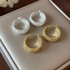 Filigrane Creolen in Gold und Silber auf einer Schmuckschatulle, elegantes Detailfoto