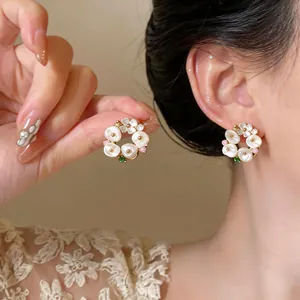 Detailed view of elegant French vintage floral pearl wreath stud earrings worn by model.