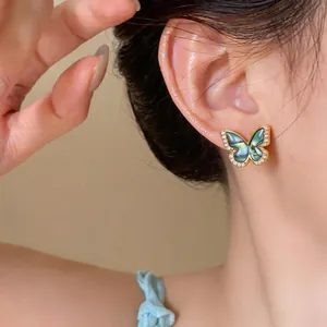 Close-up detail of 18k gold plated butterfly stud earrings with zircon stones.