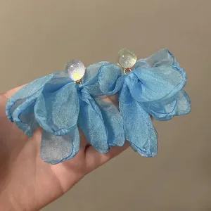 Close-up detail of elegant light blue chiffon flower stud earrings with shimmery beads