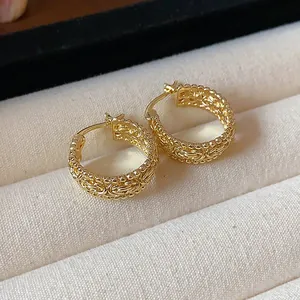 Nahaufnahme von goldfarbenen Creolen mit filigranem Gittermuster und Perlendetails