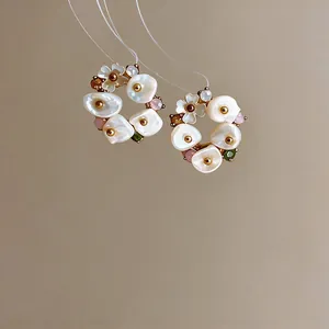 Close-up of French retro flower earrings with pearl petals and colored stones