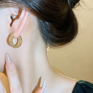 Detailaufnahme von elegantem goldfarbenem Reifenohrring mit hohlem Vintage-Muster