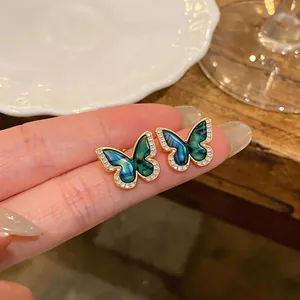 Macro close-up of vintage butterfly earrings with green enamel and zircon details