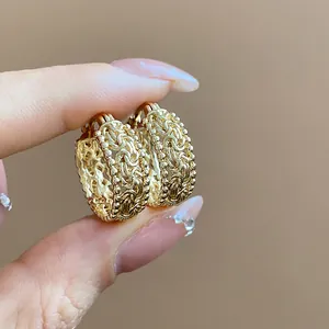 Detailansicht von goldenen, hohl gearbeiteten Creolen mit filigranem Vintage-Muster