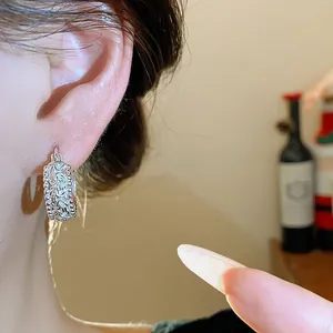 Filigrane silberne durchbrochene Creolen an einem Ohr Modell mit Vintage-Textur.