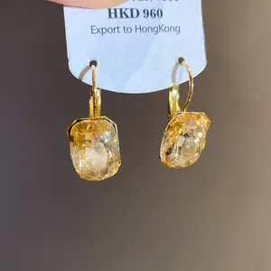 Detailed macro view of square faceted honey yellow drop earrings with gold plating