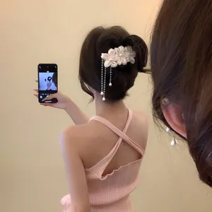 Close-up detail of a sweet floral hair clip featuring elegant pearl tassels on a model's hair