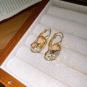 Close-up of elegant champagne square crystal pendant earrings in a wooden box