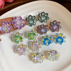 Close-up view of colorful faceted glass flower stud earrings displayed on a white ceramic plate