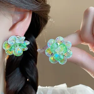 Detailed macro view of vibrant green faceted glass flower earrings on a model's ear.
