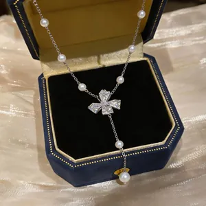 Close-up of elegant pearl bow pendant necklace with sparkling zircon details in a gift box