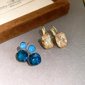 Close-up of square faceted crystal drop earrings in blue and champagne gold tones