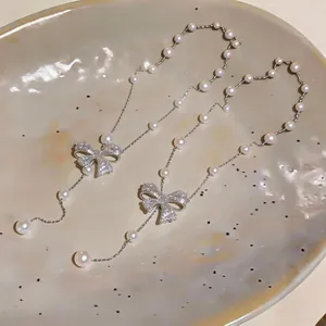 Macro view of pearl bow pendant necklace with sparkling zircons and delicate beads.